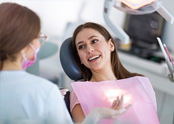 Woman in dental chair talking to dentist
