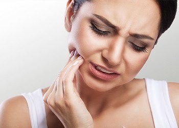 Woman in pain holding cheek